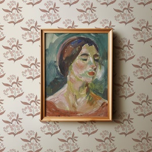 May include: A framed painting of a woman's portrait. The woman has dark hair and is wearing a light blue headscarf. The painting is set against a light green background with brushstrokes visible. The frame is a simple gold color.