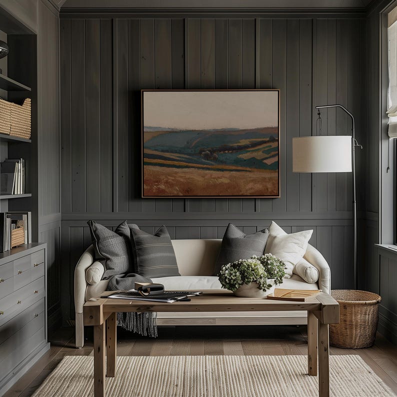 May include: A cozy living room with a neutral color palette. A cream-colored sofa is adorned with gray pillows, and a wooden coffee table holds a decorative bowl. A landscape painting hangs above the sofa, and a floor lamp provides soft lighting.