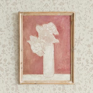 May include: A framed painting of a white flower arrangement in a white vase against a pink background.