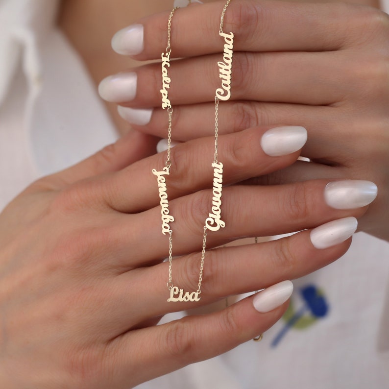 May include: Gold necklace with five personalized nameplates. The names on the necklace are "Lisa", "Giovanni", "Jeneveba", "Hallie", and "Caitlin".