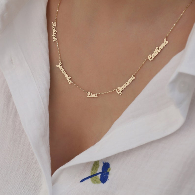 May include: Gold necklace with five names on it:  'Kalyn', 'Jenaueha', 'Lisa', 'Giovanni', and 'Cassland'.