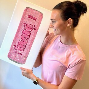 K&ouml;nnte beinhalten: Rosa Leinwandkunst mit einem glitzernden Soda-Dosen-Design mit dem Wort "Freno" in einer Blasen-Schriftart. Das Kunstwerk enth&auml;lt den Text "KIMADE" oben und "BY KIM K" unten. Das Dosen-Design ist mit Glitzer bedeckt.