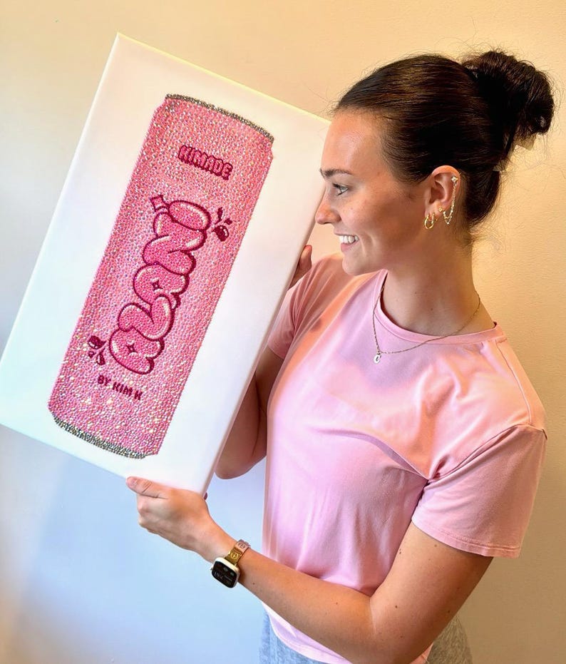 K&ouml;nnte beinhalten: Rosa Leinwandkunst mit einem glitzernden Soda-Dosen-Design mit dem Wort "Freno" in einer Blasen-Schriftart. Das Kunstwerk enth&auml;lt den Text "KIMADE" oben und "BY KIM K" unten. Das Dosen-Design ist mit Glitzer bedeckt.