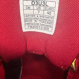 May include: Close-up of the inside of a red shoe. A white tag displays size information: UK 7, Euro 40. The shoe is made with leather and synthetic materials, with a rubber sole. The tag also indicates the shoe was made in Thailand.