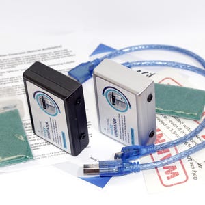 May include: Two colloidal silver generators, one black and one silver, with blue USB cables and green pads. The devices have labels with text and a circular design. Additional printed materials are also present.