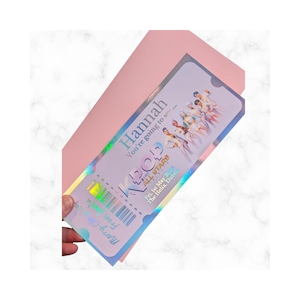 May include: A holographic K-Pop concert ticket with the name "Hannah" printed in a light blue font. The ticket includes the text "You're going to see..." and "K-Pop All Stars" with the date "Fri, 1st May 202" and the venue "The Helix, Dublin."