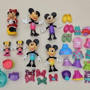 May include: A collection of Disney Mickey Mouse and Minnie Mouse figurines, including a variety of outfits and accessories. The figurines are made of plastic and are brightly colored. There are also several small accessories, such as shoes, purses, and hair bows.