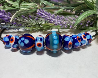 Set of 9 handmade lampwork glass beads in opaque cobalt blue with turquoise shades, pale blue, and salmon