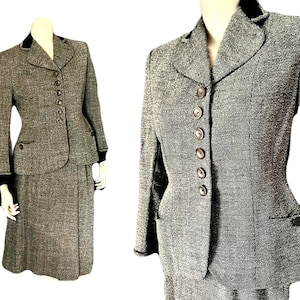 May include: A vintage gray tweed skirt suit with a fitted jacket featuring a black velvet collar and six matching buttons. The skirt is knee-length. The suit is displayed on a mannequin.