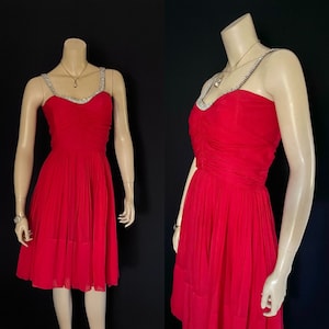 May include: A red sleeveless dress with a beaded neckline and a pleated skirt.