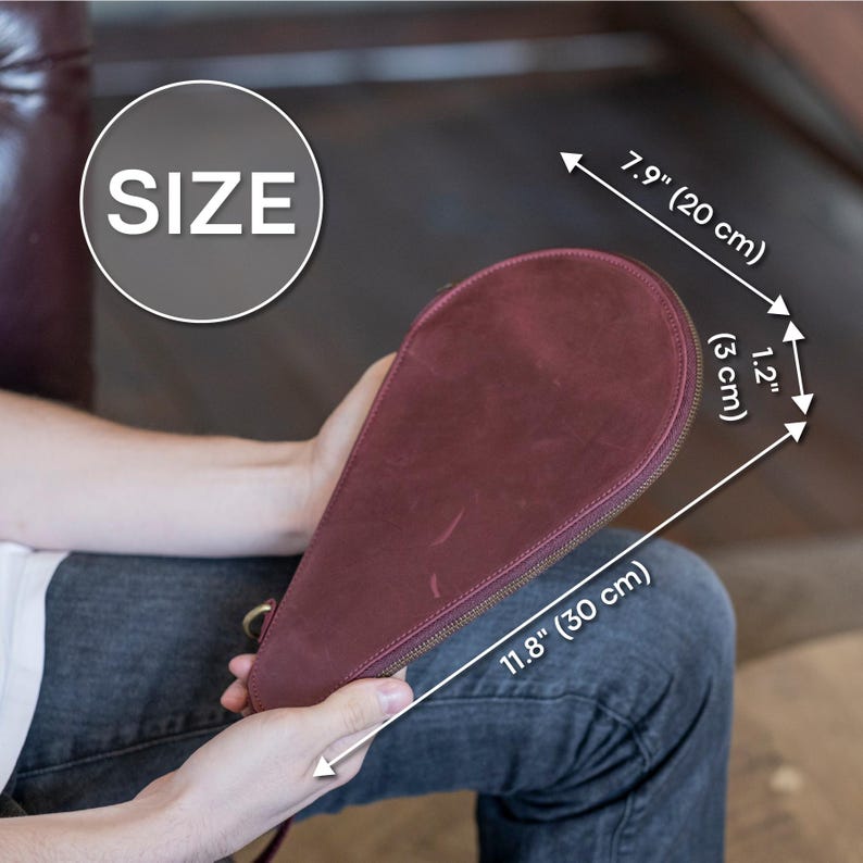 May include: A burgundy leather zippered pouch with a teardrop shape. The pouch measures 11.8 inches long and 7.9 inches wide.