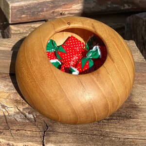 May include: A wooden bowl with a smooth, light brown finish. The bowl is filled with small, colorful candies wrapped in foil.