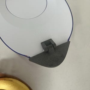 Puede incluir: Hervidor eléctrico blanco con tapa negra y borde azul. El hervidor tiene una base redonda y un asa en el lateral. La tapa está abierta y el interior del hervidor es visible.