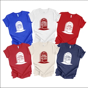 May include: Five t-shirts in different colors with a white graphic of a tombstone with the text "RIP dollar dog night 1997-2023" on it.