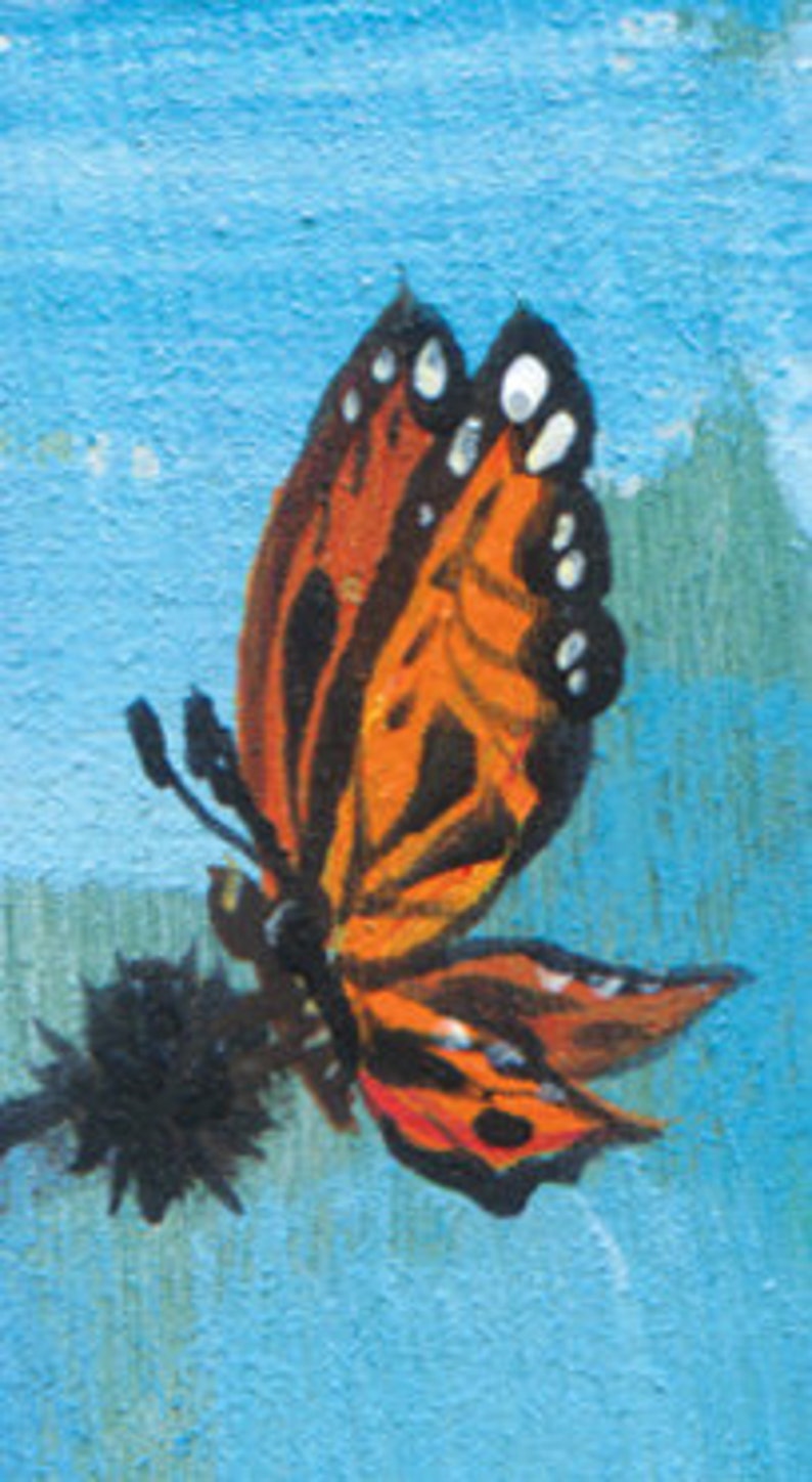 May include: A close-up of a monarch butterfly with orange and black wings, perched on a black flower with a blue background.