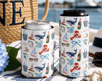 May include: Two white can coolers featuring a repeating nautical pattern of whales, lobsters, sailboats, lighthouses, champagne bottles, sunglasses, and blue bows. A circular badge in the upper right corner displays the text SLIM & REGULAR CAN.