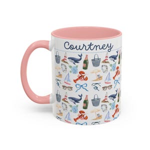 Op de afbeelding: Een witte keramische mok met een roze binnenkant en een blauw-wit nautisch patroon. Op de mok staat de naam "Courtney".