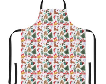 May include: White apron with a repeating Christmas-themed pattern. The pattern includes reindeer, nutcrackers, gingerbread houses, Christmas trees, wrapped gifts, Santa hats, bells, and mugs. The apron has black straps.