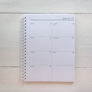 May include: A white weekly planner with a black spiral binding. The planner has a black header that reads "june 13-19". The days of the week are listed in a column on the left side of the planner, and the dates are listed in a row across the top of the planner.