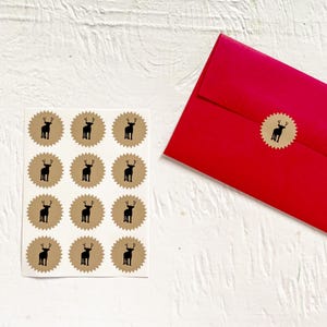 May include: A sheet of 12 brown paper circle stickers with a black silhouette of a reindeer on each sticker. The stickers are arranged in a 4x3 grid. A red envelope is in the background.