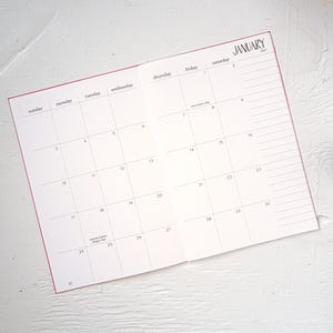 May include: An open planner showing a monthly calendar for January 2027. The grid layout includes days of the week from Sunday to Saturday, with specific dates numbered 1 through 31. It features text for New Year's Day and Martin Luther King Jr. Day.