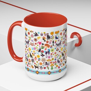 May include: White ceramic mug with a red interior and handle, adorned with a colorful pattern of animals, flowers, and hearts. The design includes cats, dogs, and other whimsical elements. A turquoise band with geometric shapes encircles the base.