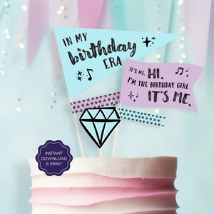 May include: A cake topper with a blue diamond and two flags. The flags are light blue and purple with the text "In my birthday era" and "It's me. Hi. I'm the birthday girl. It's me."