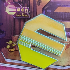 May include: A yellow and silver enamel pin shaped like the letter "S" with a retro design. The pin has a textured surface and a shiny finish. The pin is a collectible item and is perfect for fans of retro design.