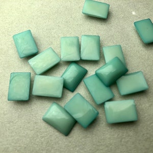 May include: A group of 13 light blue rectangular glass tiles. The tiles are scattered on a white surface.