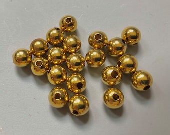 May include: A pile of gold-colored metal beads with a hole in the center of each bead.