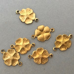 Puede incluir: Seis abalorios de metal dorado en forma de flor con dos anillos de salto en cada uno. Los abalorios de flor son todos del mismo tamaño y forma, con cinco pétalos y un círculo central.