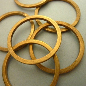 May include: A set of five gold-colored metal rings, each with a smooth, rounded surface. The rings are interlocked, creating a decorative and intricate design.