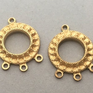 Könnte beinhalten: Zwei runde Anhänger-Verbindungscharms aus goldfarbenem Metall mit einem dekorativen, strukturierten Rand und drei Sprungringen.