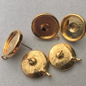 May include: Four gold-toned metal earring settings with a round shape and a post on the back. Two of the settings have a loop on the side, and two have a post on the back.