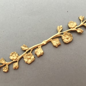 Puede incluir: Adorno floral de metal dorado con un delicado diseño de rama y cinco flores. El adorno es perfecto para agregar un toque de elegancia a las manualidades, las joyas y otros proyectos.