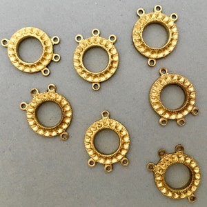 May include: Six gold-toned metal connector charms with a decorative design. Each charm has a circular center with three loops extending from the edge.