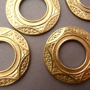 Peut inclure: Quatre anneaux en métal couleur or avec des motifs complexes. Chaque anneau a une ouverture circulaire au centre.