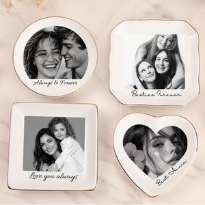 May include: Four white ceramic trinket dishes with gold-toned rims, each featuring a black and white photograph and printed text. The dishes are round, square, and heart-shaped, displaying the phrases Always & Forever, Besties Forever, Love you always, and Best Annie.
