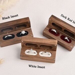 Puede incluir: Tres cajas de madera para anillos con insertos de terciopelo de diferentes colores. Las cajas est&aacute;n abiertas y muestran dos anillos en cada caja. Las cajas est&aacute;n etiquetadas como "Black Insert", "Dark Red Insert" y "White Insert".