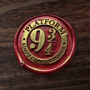 May include: A red and gold circular emblem with the text "PLATFORM 9 3/4" and "KING'S CROSS LONDON". The emblem is a Harry Potter-themed design, with a gold-colored number 9 and the fraction 3/4.