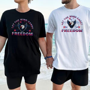 フライングイーグル ユニセックスTシャツ、独立記念日 風に自由を運ぶTシャツ、男性と女性へのギフト、愛国的なグラフィックシャツ、アメリカーナトップシャツ