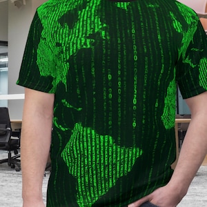 May include: Black crew neck t-shirt with a green digital rain pattern forming a world map design. The shirt has a black collar and short sleeves. The graphic is a matrix-style design, with vertical lines of green characters over a dark background.