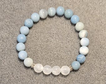 May include: A blue and white gemstone bracelet with silver accents. The bracelet is made of round beads and has a gradient of blue shades.