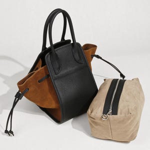 K&ouml;nnte beinhalten: Eine schwarze und braune Ledertasche mit Kordelzug und einer separaten braunen Tasche.