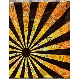 Może przedstawiać: Kołdra z wzorem promieni słonecznych. Środek to ciemnobrązowe koło, z promienistymi paskami w odcieniach żółci, pomarańczy i brązu. Paski wypełnione są geometrycznymi kształtami, w tym trójkątami i szewronami.