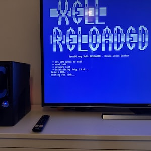 May include: A blue screen displaying the text "XeLL RELOADED" and the message "Freet0.org XeLL RELOADED - Xenon Linux Loader" followed by a list of commands. A black external hard drive with a blue light is in the foreground.