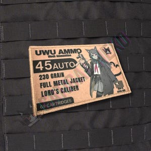 May include: A rectangular patch with the text "UWU AMMO" and "45 AUTO" in black. The patch also features the text "230 GRAIN FULL METAL JACKET LORD'S CALIBER" and an anime-style illustration of a character holding a gun. The patch is tan with a black background.