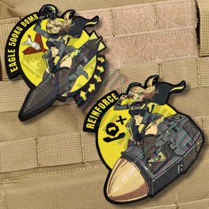 May include: Two embroidered patches featuring a cartoon anime-style character riding a bomb. One patch reads "EAGLE 500KG BOMB" and the other reads "REINFORCE". The patches have a yellow and black color scheme.