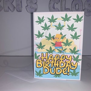 May include: A birthday card featuring Bart Simpson with arms raised, surrounded by green cannabis leaves. The words "HAPPY BIRTHDAY DUDE!" are in a colorful, playful font. The card has a white border and is set against a light background.