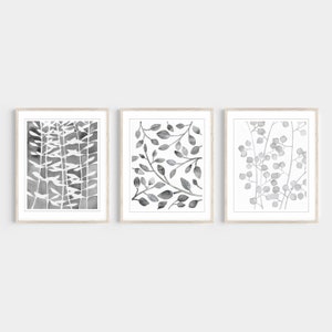 May include: Set of three framed black and white watercolor prints featuring abstract botanical illustrations. The prints are in simple white frames.